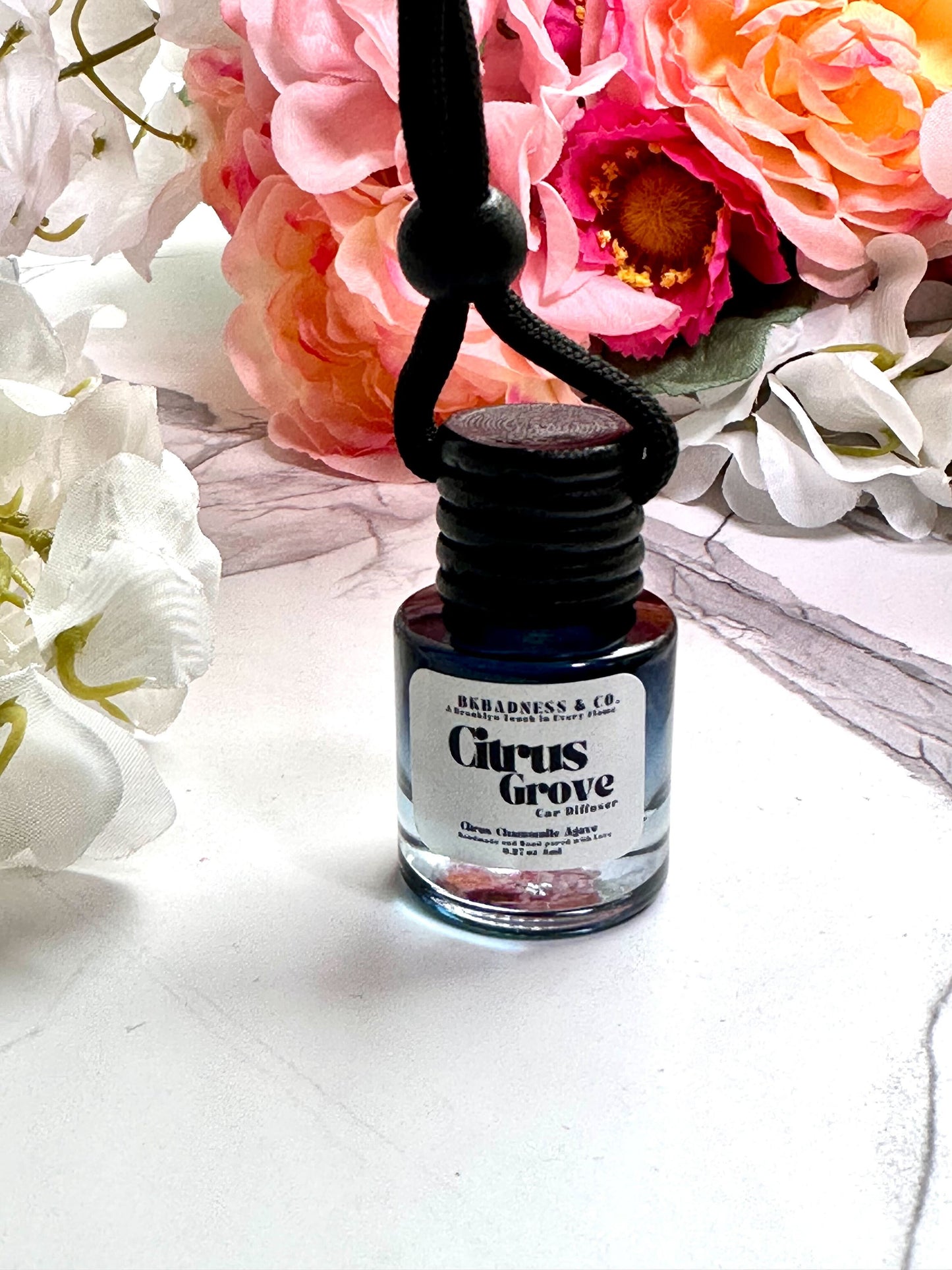 Bottle of 'Citrus Grove' cologne with flowers in the background