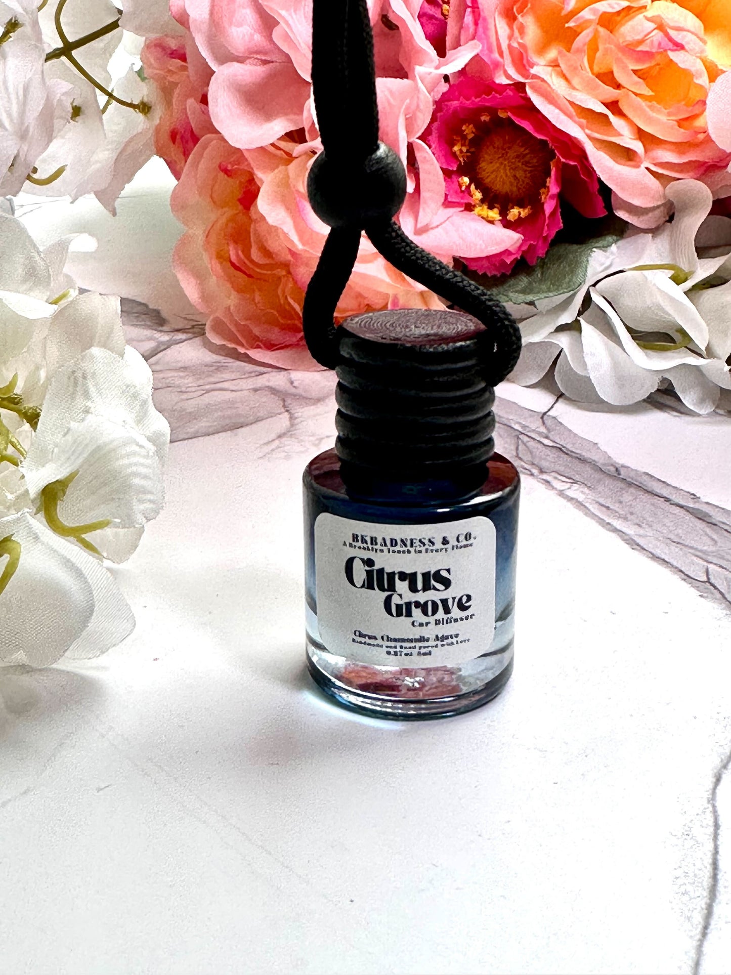 Bottle of 'Citrus Grove' cologne with flowers in the background