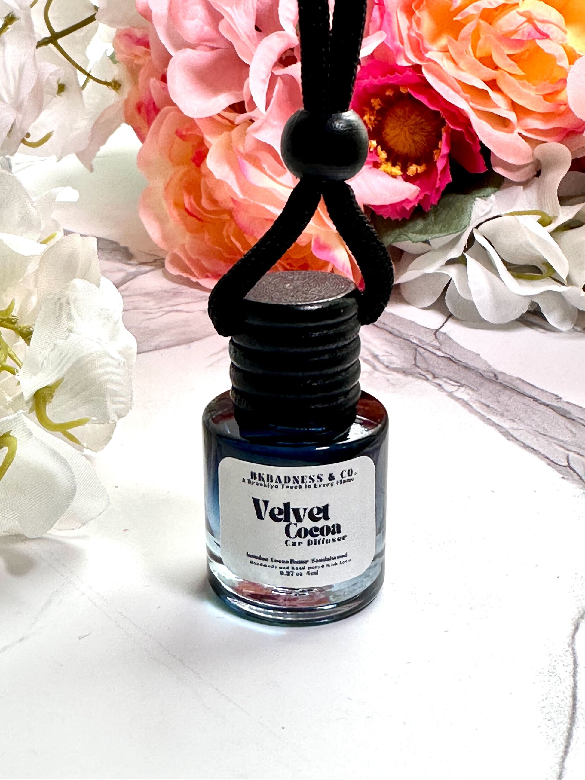 Bottle of 'Velva Cocoa' perfume with flowers in the background
