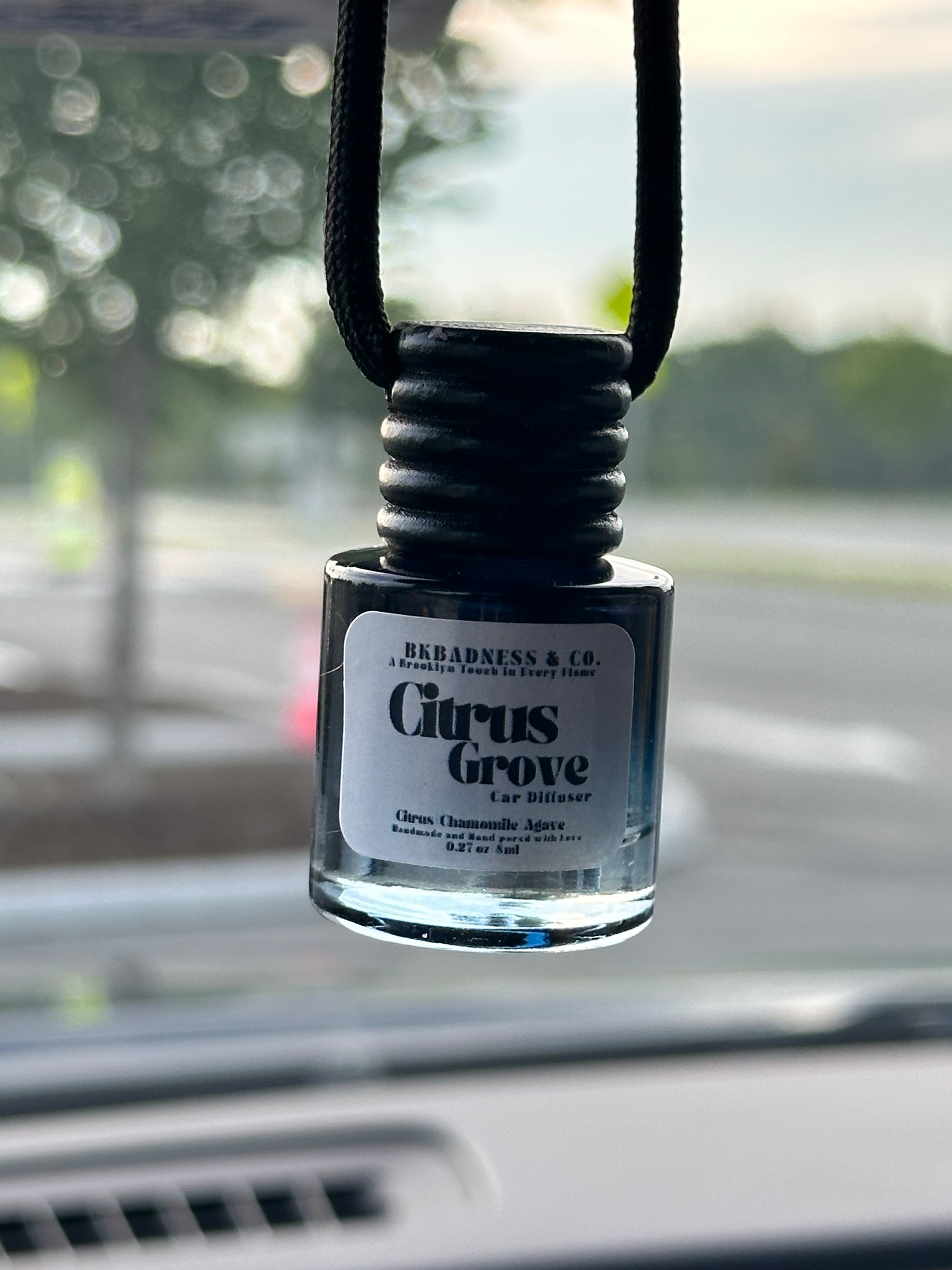Car air freshener with 'Citrus Grove' label attached to a car's air vent.