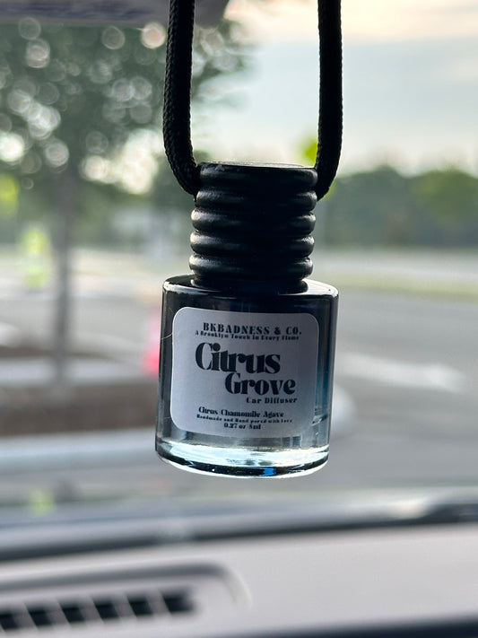 Car air freshener with 'Citrus Grove' label attached to a car's air vent.
